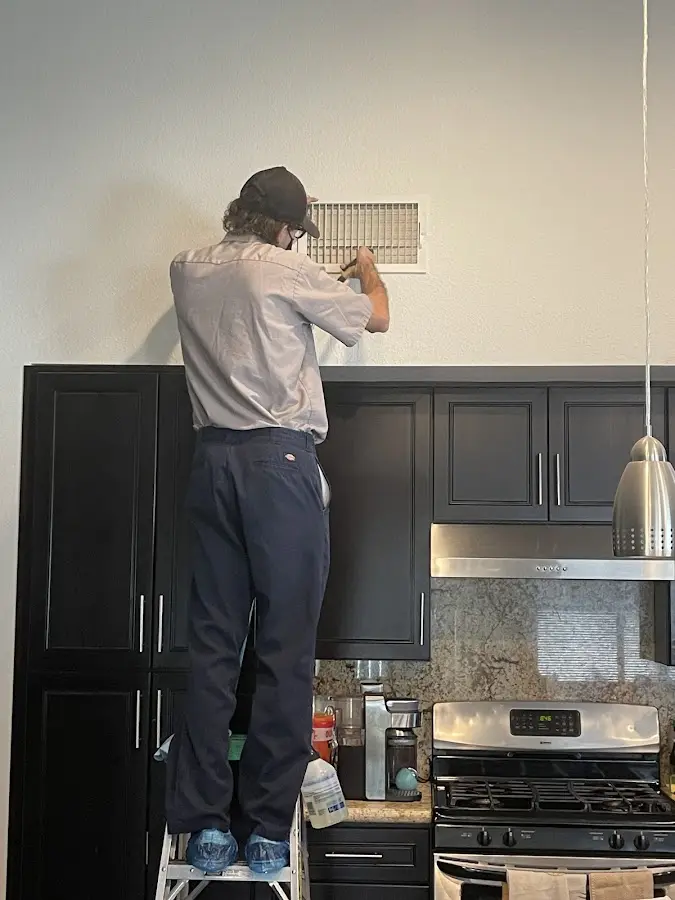 Technician inspecting an air vent during HVAC service in Meadville